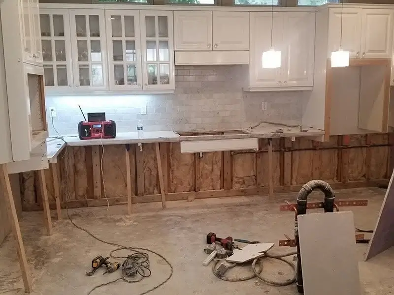 Kitchen under renovation with exposed walls and tools on the floor.